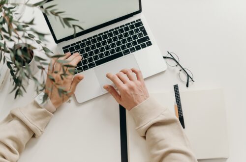 a laptop on a white background with glasses on the side and a handing typing